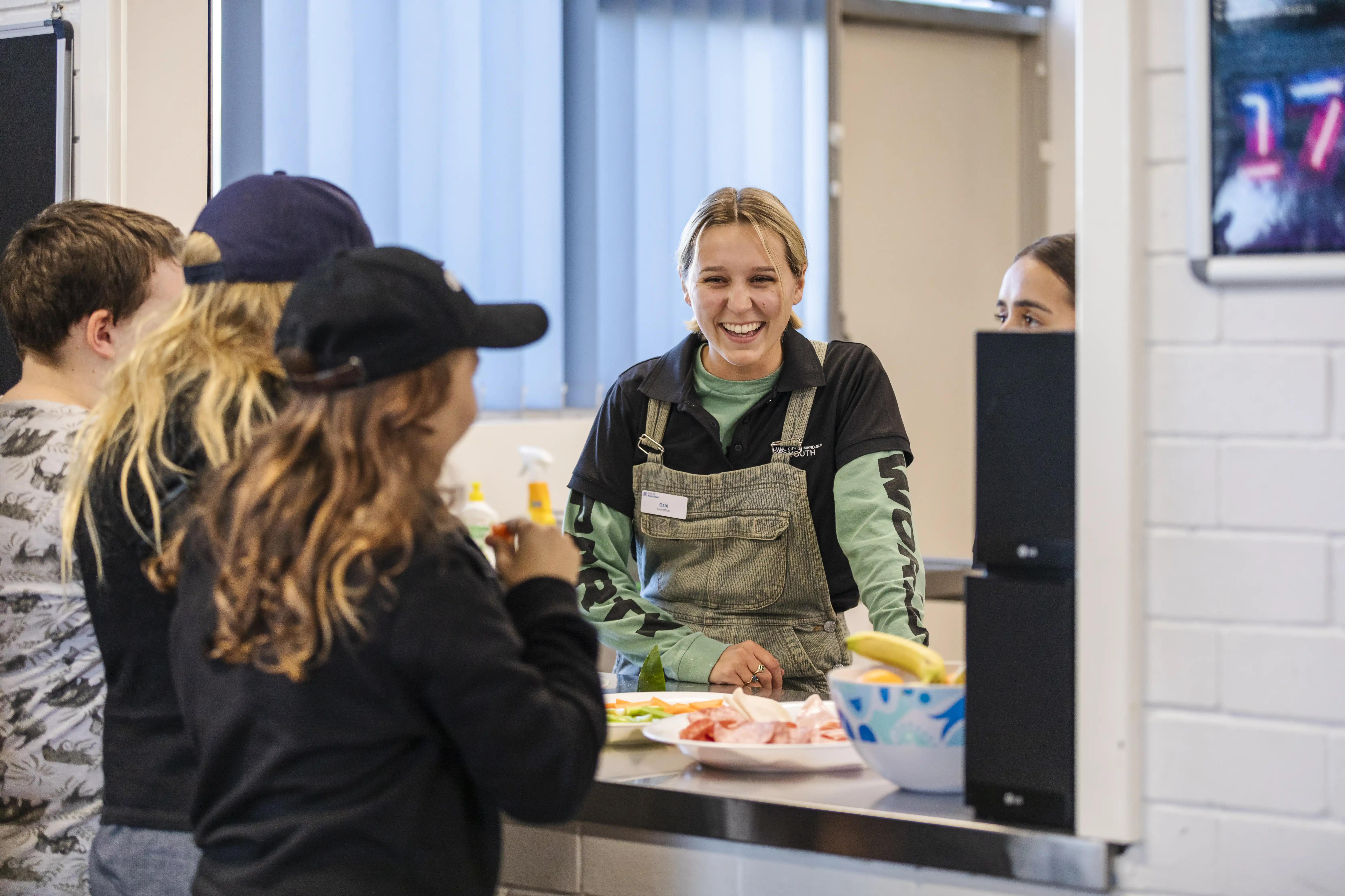 People in kitchen with snack food.